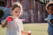 girl-in-white-shirt-holding-pink-plastic-toy-with-bubbles